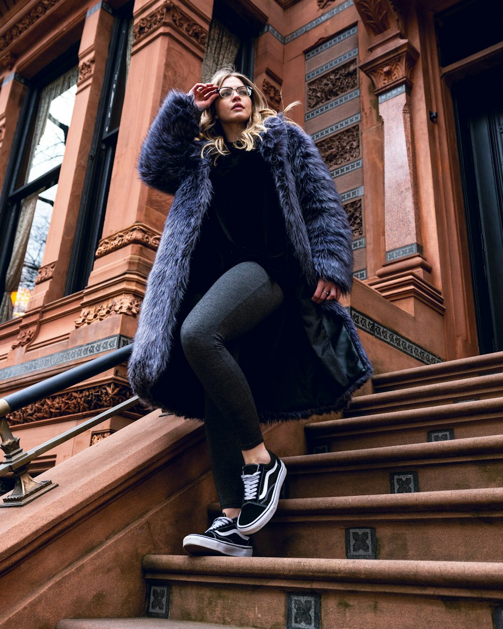 woman in black fur coat sitting on brown wooden staircase