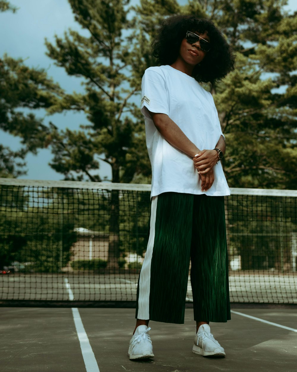 woman in white shirt and green skirt standing on tennis court