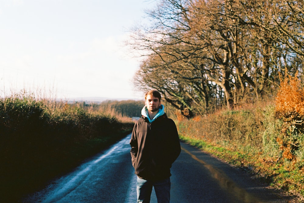 man in black jacket standing on road during daytime