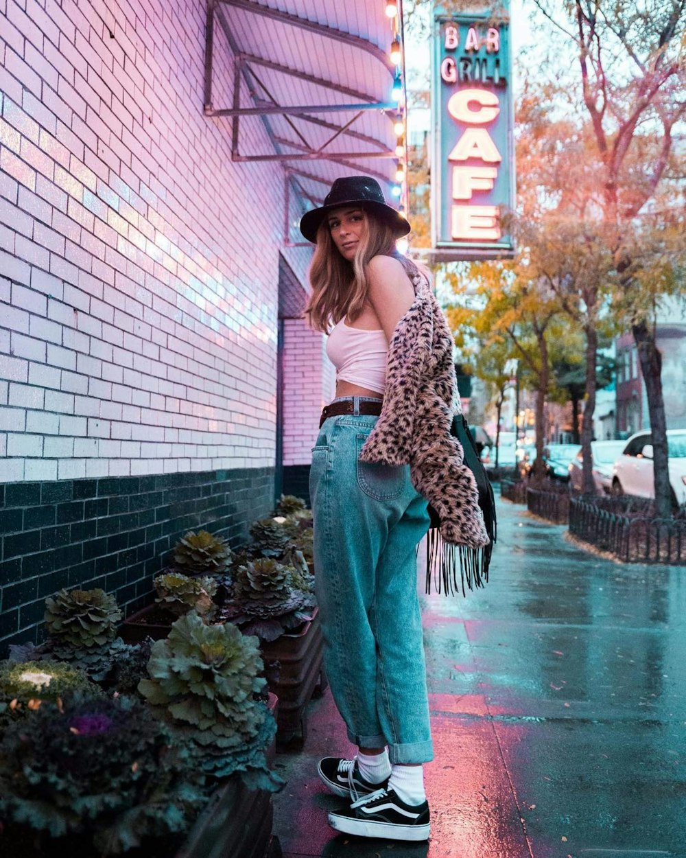 woman in leopard print cardigan and red pants standing on sidewalk during daytime