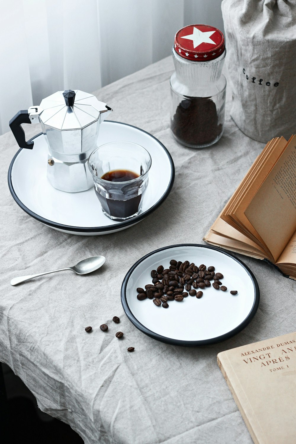 white ceramic teacup on white ceramic saucer beside stainless steel spoon