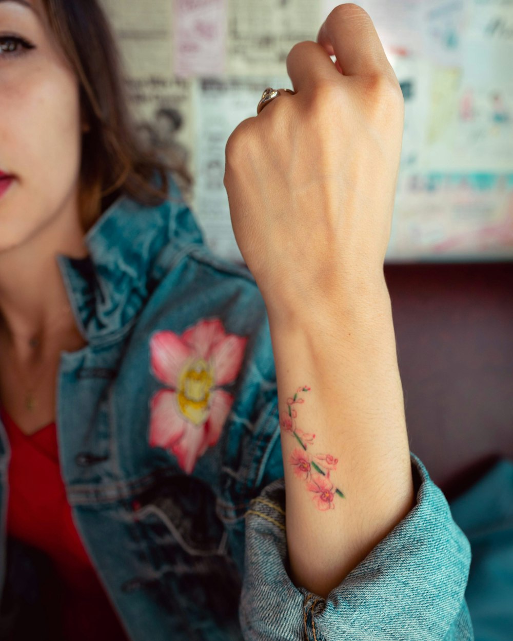 woman in blue denim jacket with black floral tattoo on left hand