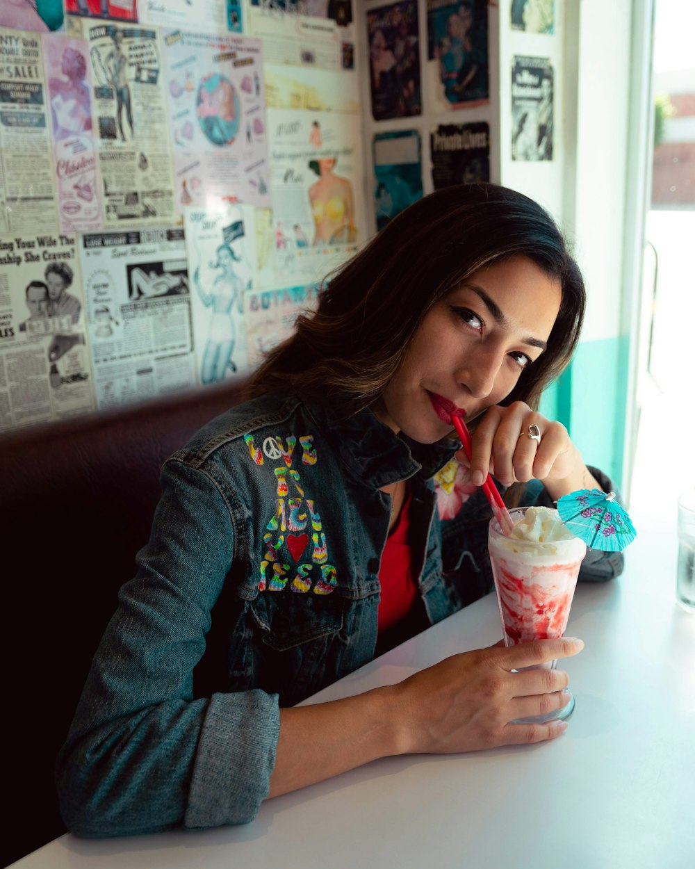 woman in red and blue jacket holding clear plastic cup