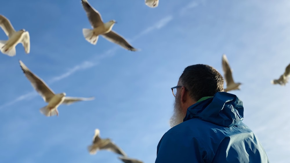 man in blue jacket looking at white birds