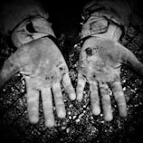 A close-up of hands clasped in solidarity, dirt and sweat visible.