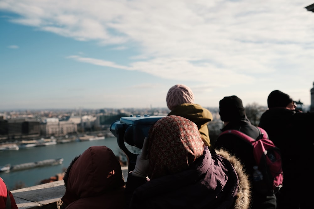 people sitting on the ground looking at the sea during daytime