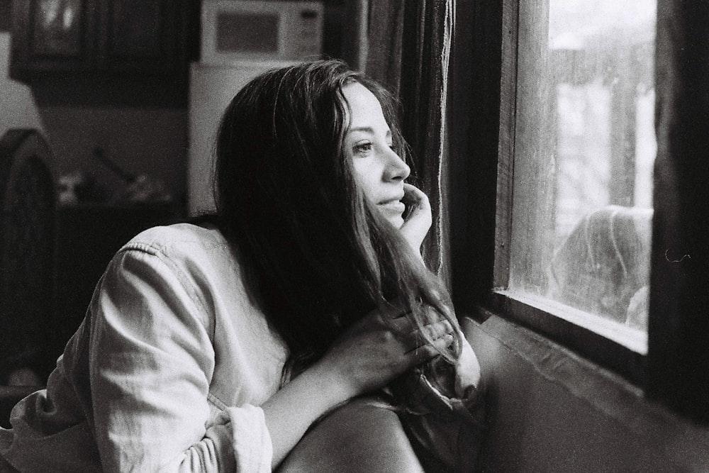 woman in white sweater sitting beside window