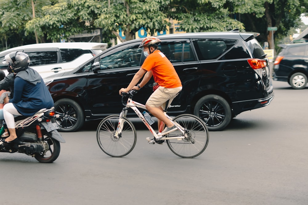 man in orange t-shirt riding on white bicycle