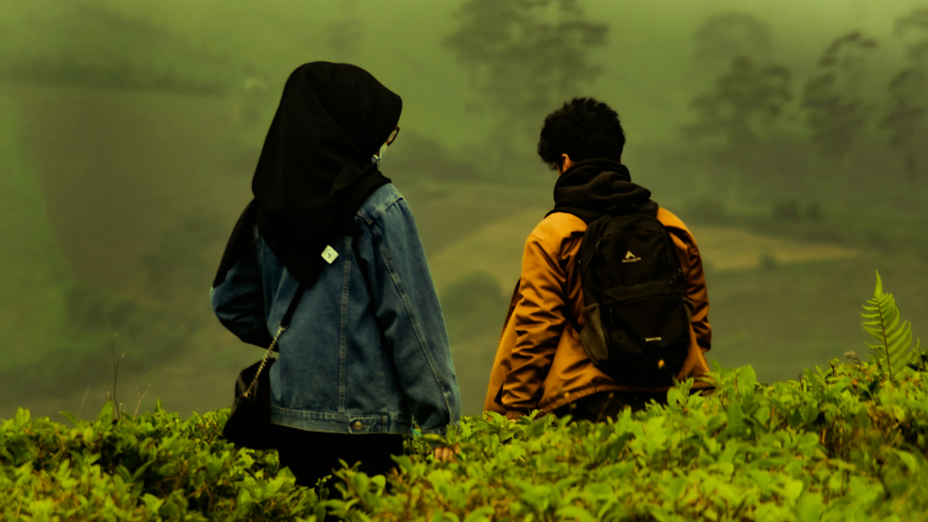 Pria dan wanita mengenakan jaket denim biru berdiri di lapangan rumput hijau di siang hari
