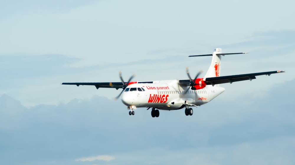 white and red air plane in mid air during daytime