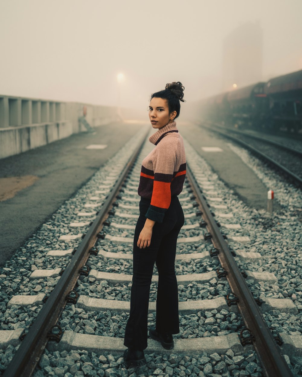 woman in red and black long sleeve shirt and black pants standing on train rail during