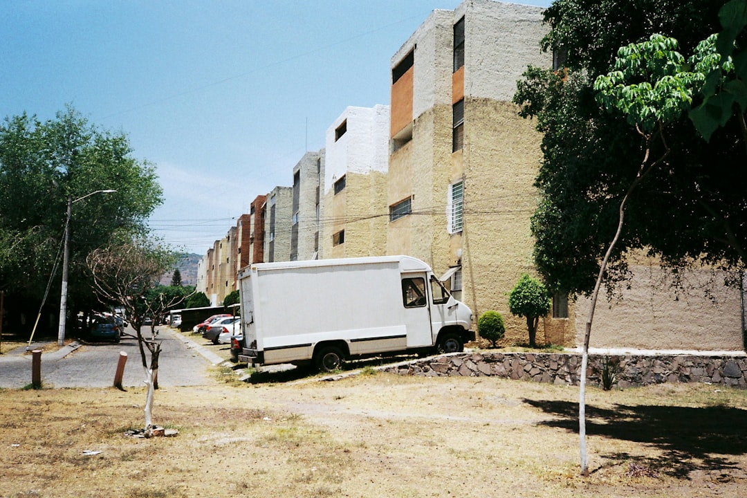 white van parked beside brown concrete building during daytime