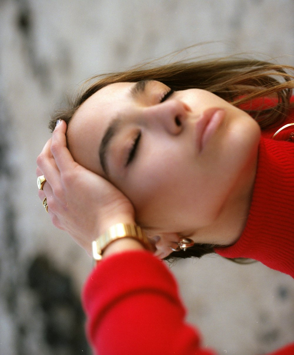 woman in red sweater holding her face