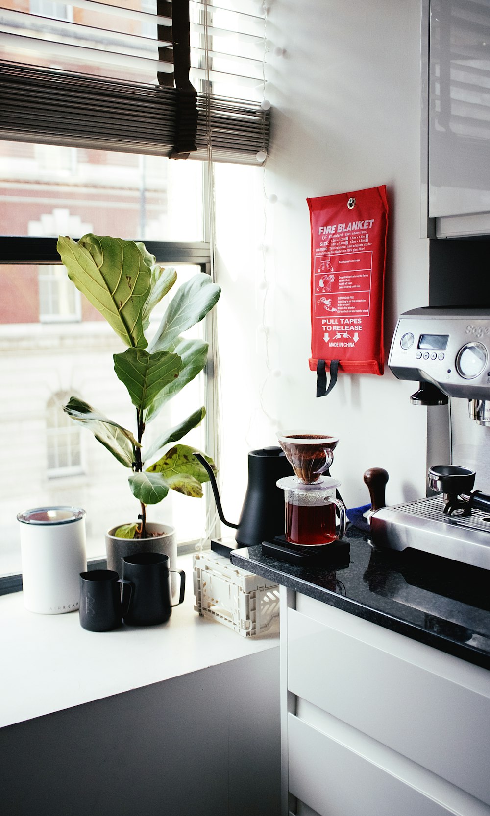 Cafetera roja y plateada junto a taza de cerámica blanca