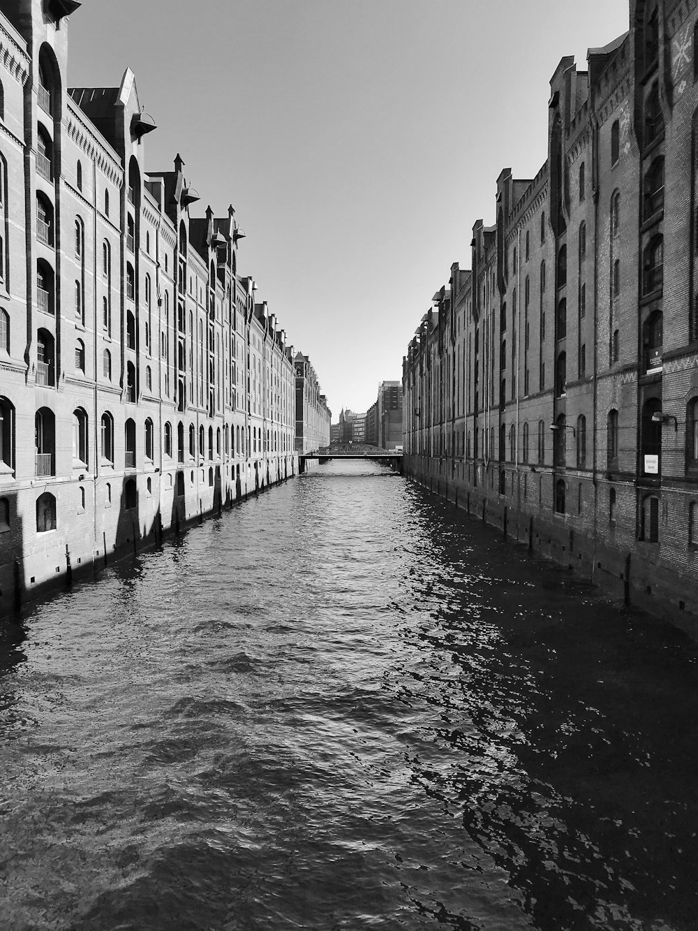 grayscale photo of river between concrete buildings