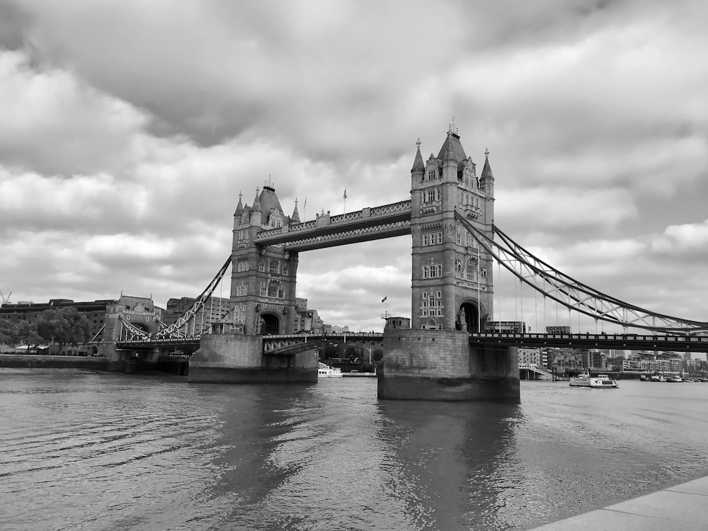 grayscale photo of bridge under cloudy sky