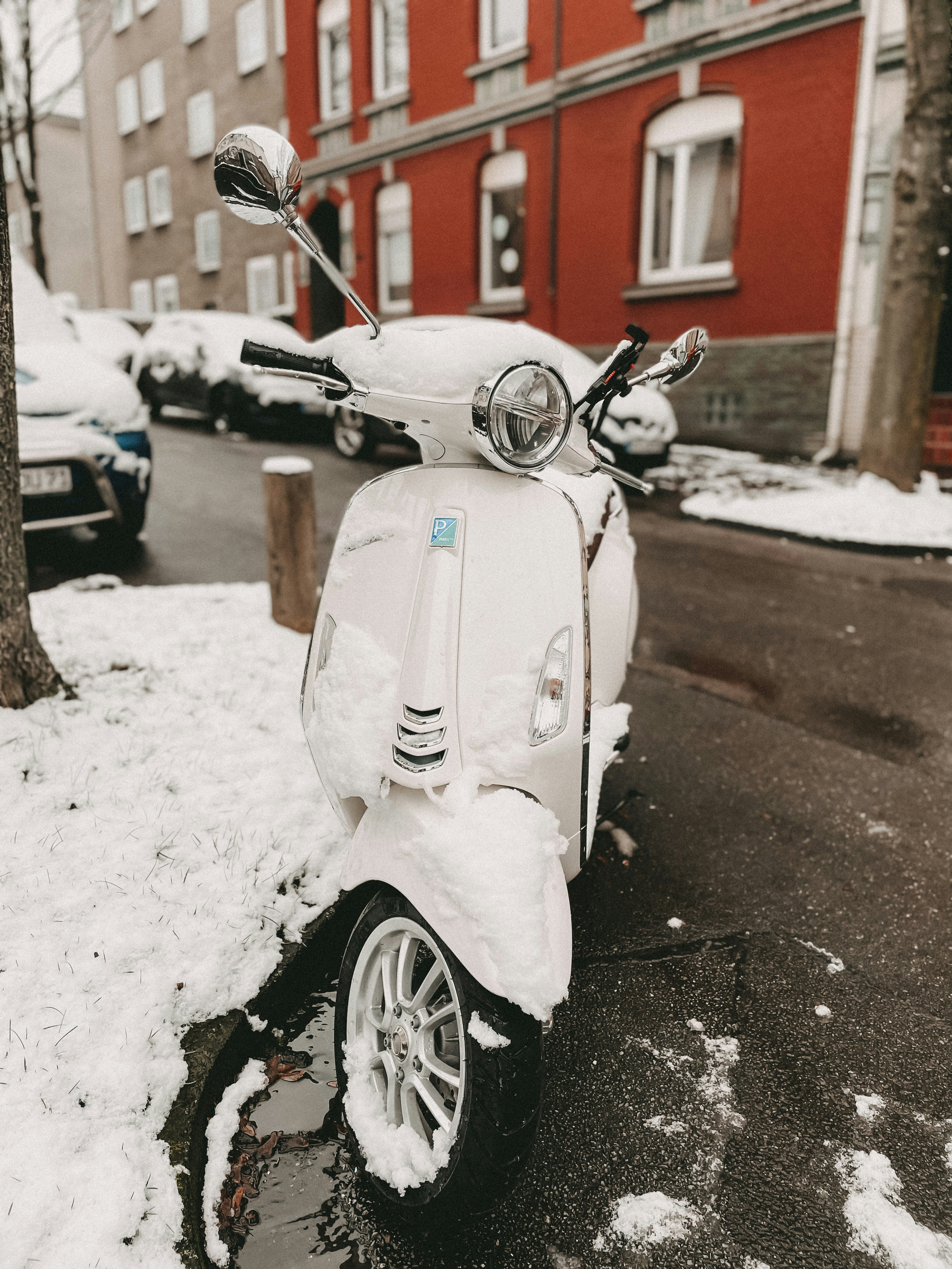 white motor scooter parked on street during daytime