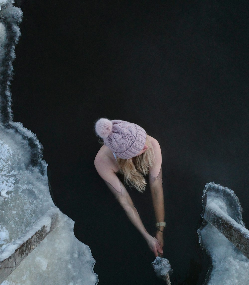 woman in pink knit cap and brown shirt climbing on rock
