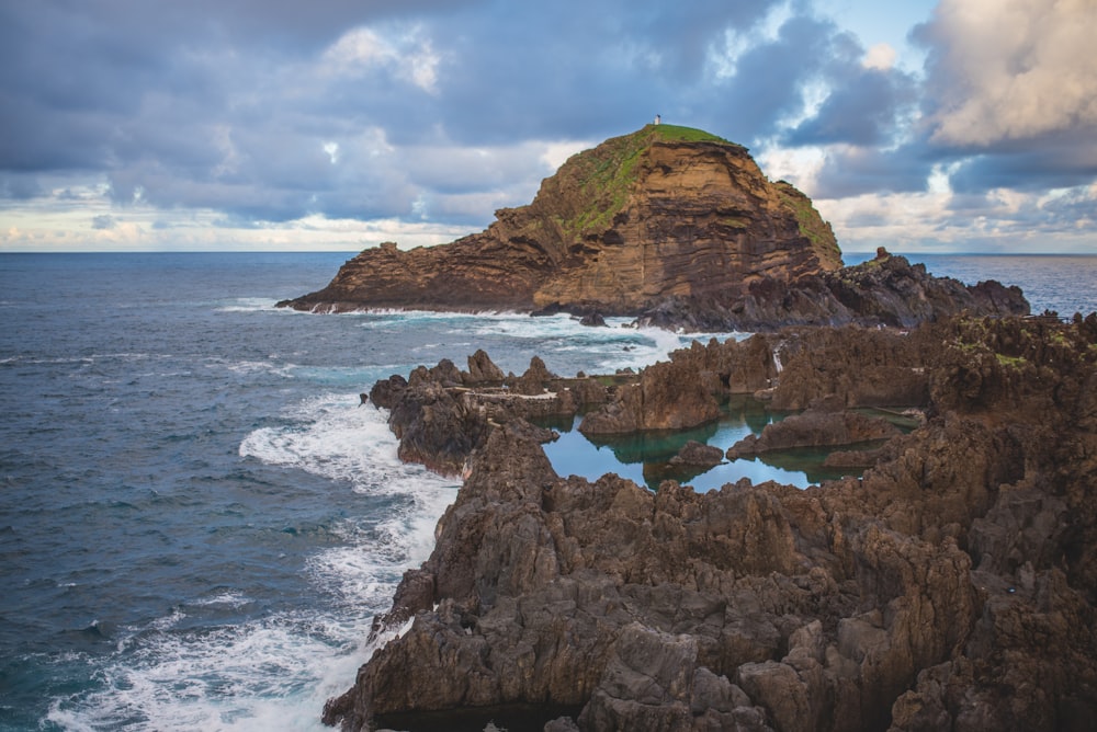 brown rock formation on body of water during daytime