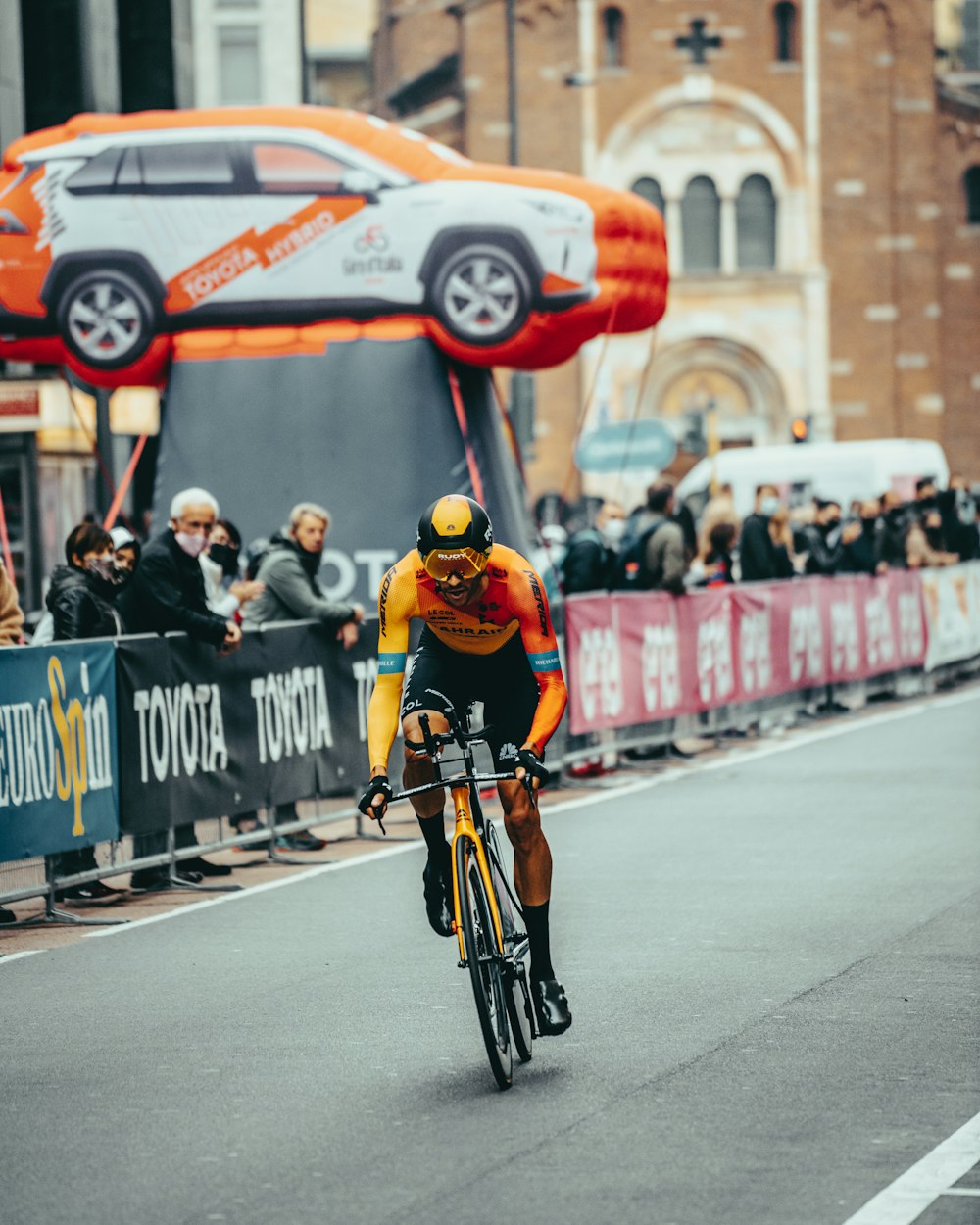 man in orange helmet riding bicycle on road during daytime