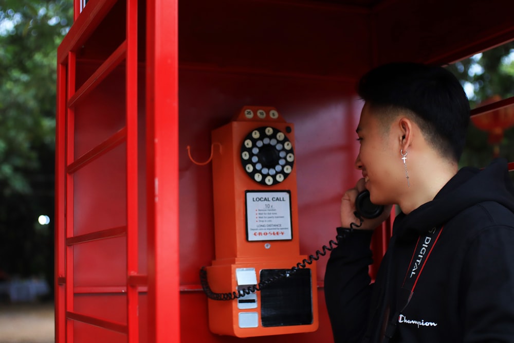 woman in black jacket holding black and red telephone