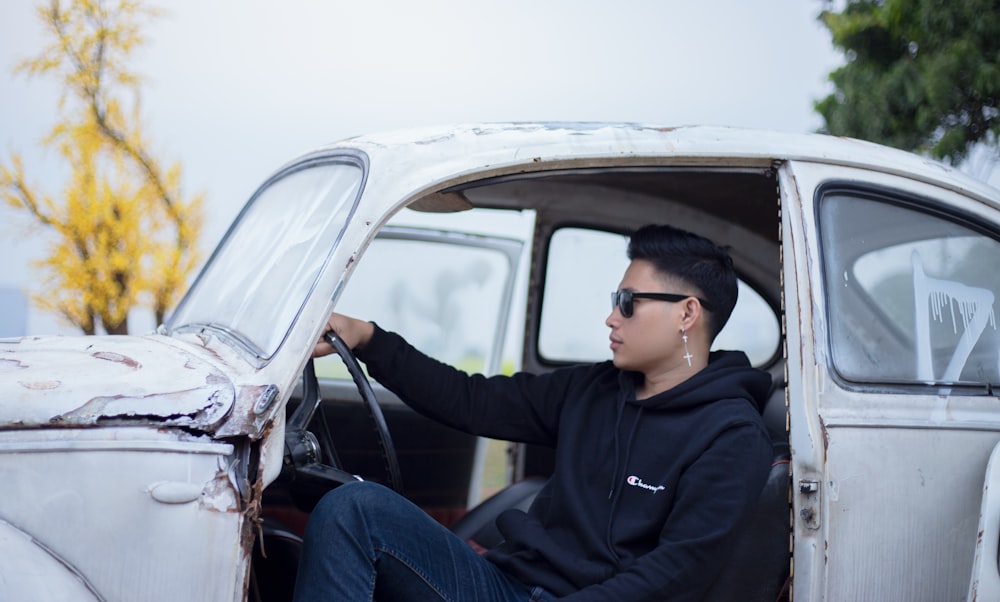 man in black jacket sitting on car