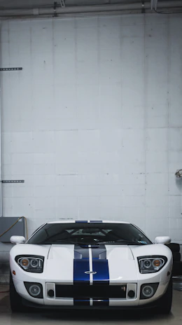 Racing stripe kit installation in progress on a blue muscle car in a garage setting.