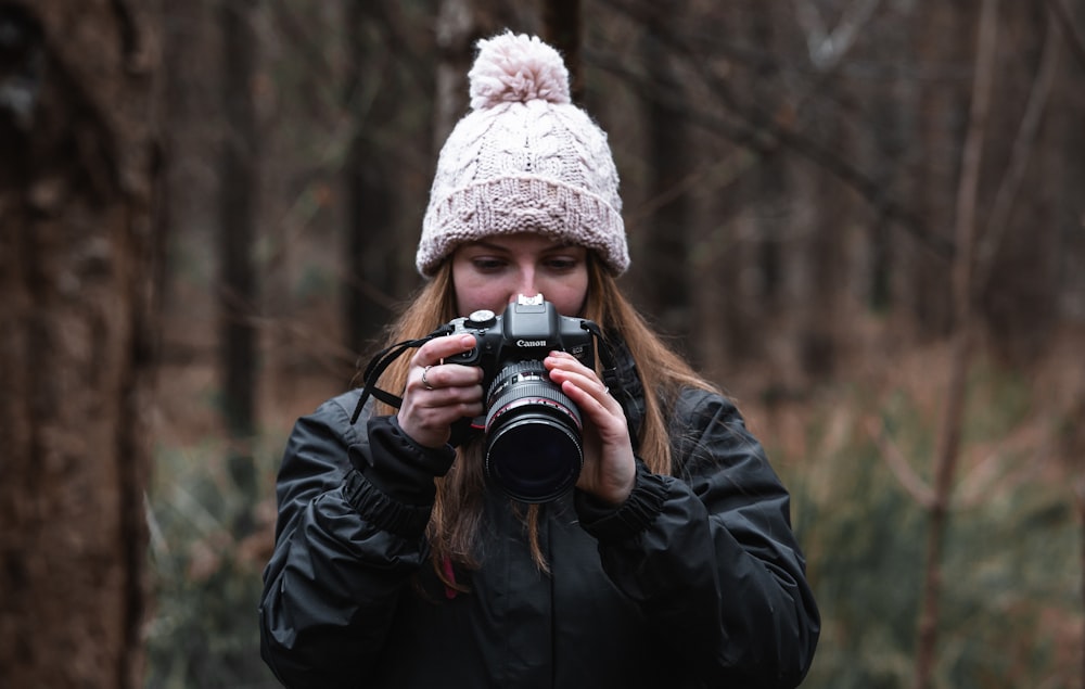 woman in black jacket holding black dslr camera