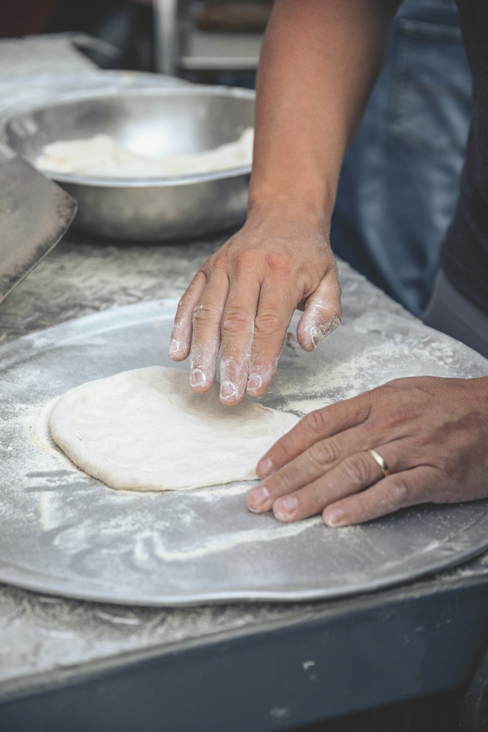 person holding white dough on stainless steel tray