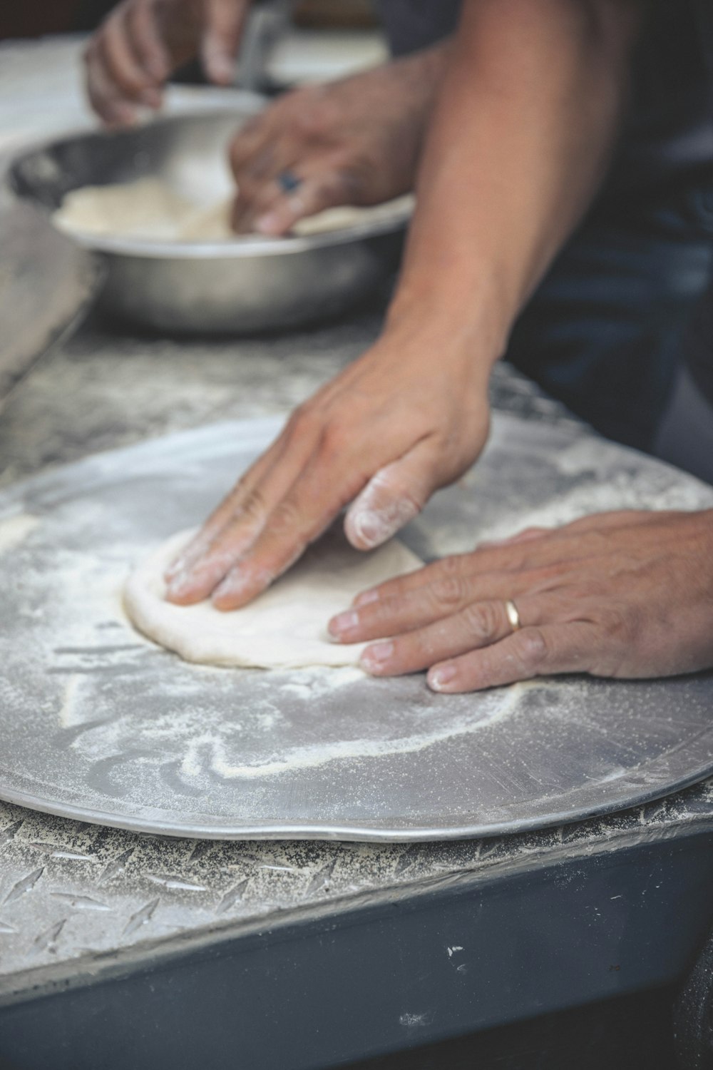 person holding white dough on stainless steel tray