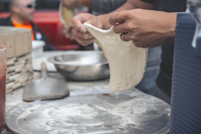 Artisan dough being hand-stretched in a rustic kitchen setting.