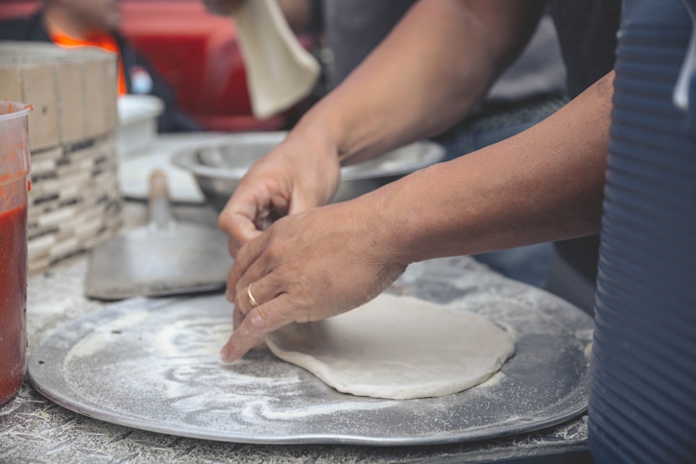 person holding white dough on white table