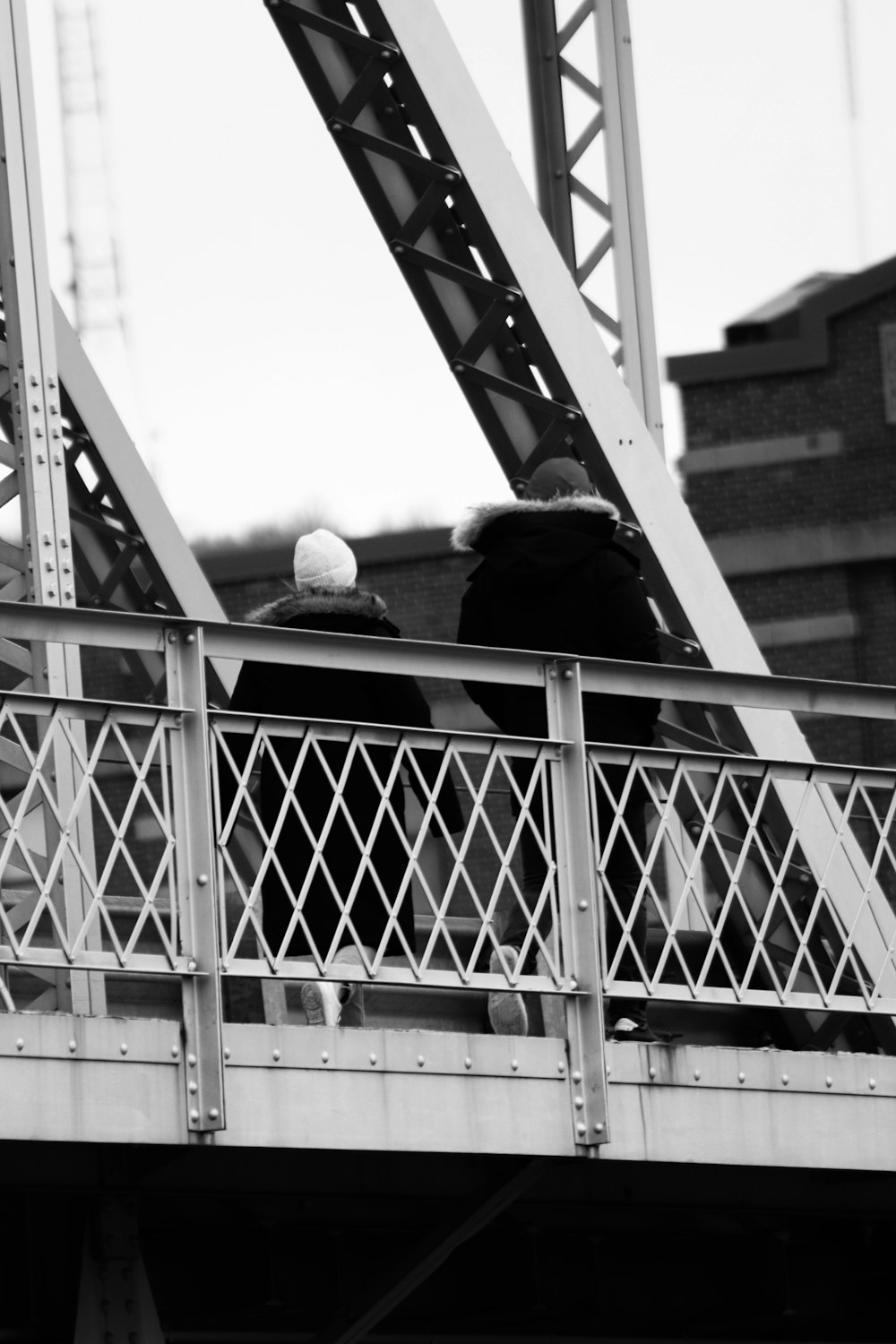 grayscale photo of man and woman kissing on the bridge
