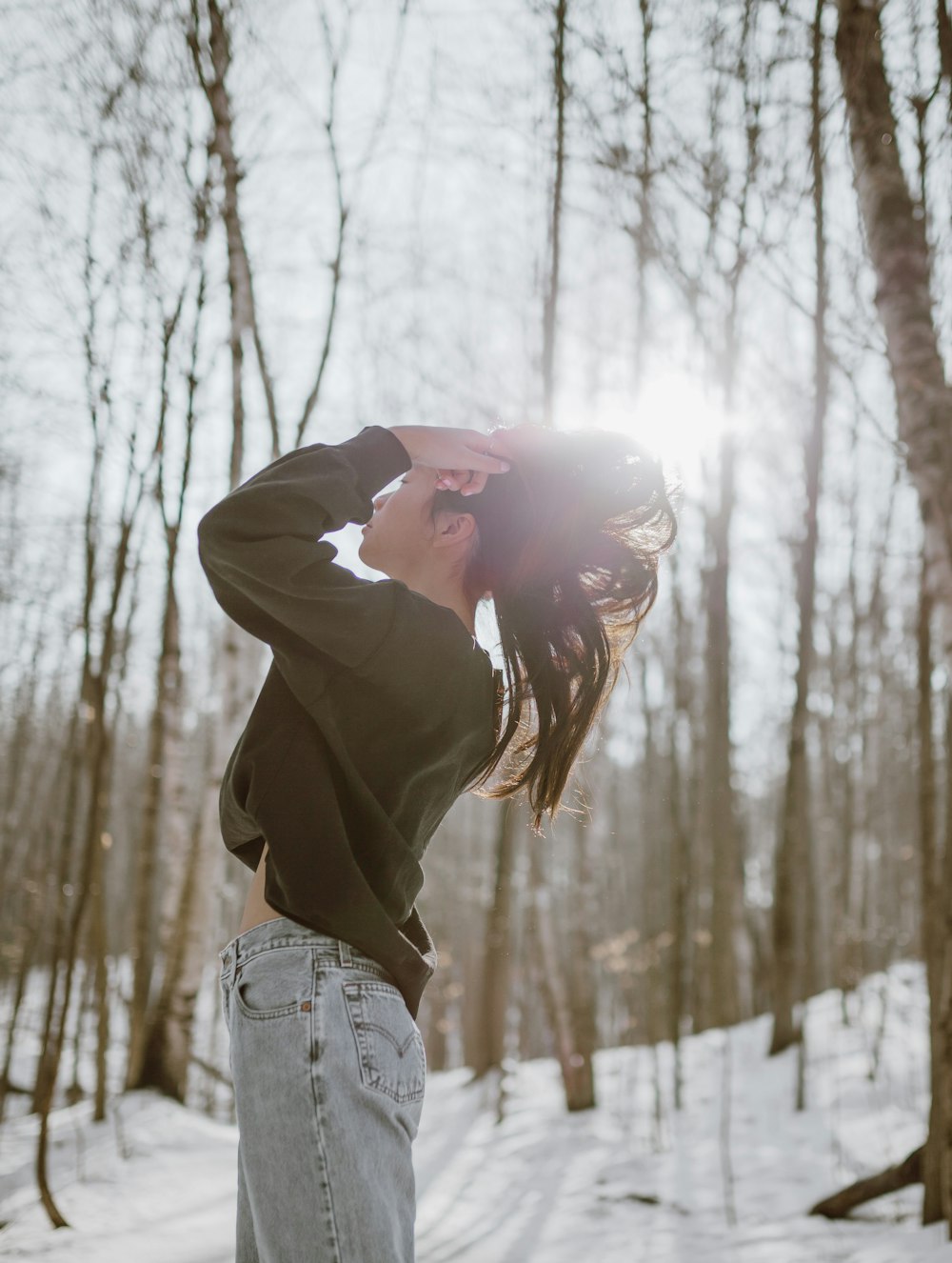 woman in brown hoodie standing on snow covered ground during daytime