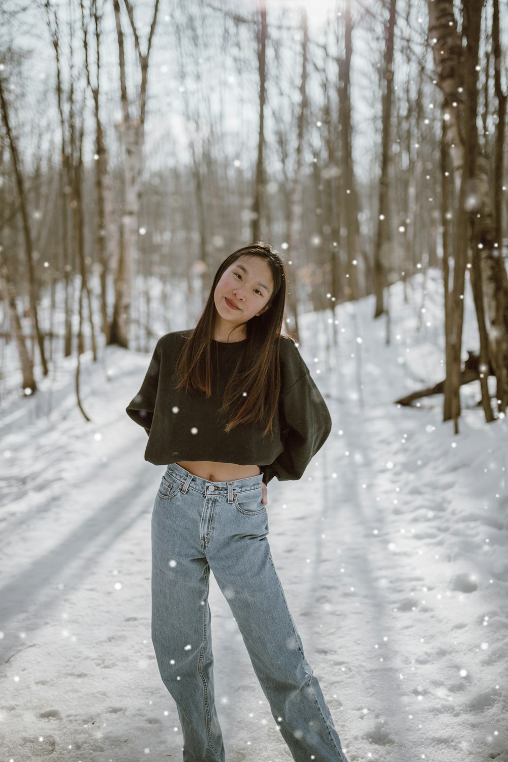 Donna in giacca marrone e jeans blu in denim che si leva in piedi su terreno coperto di neve durante il giorno