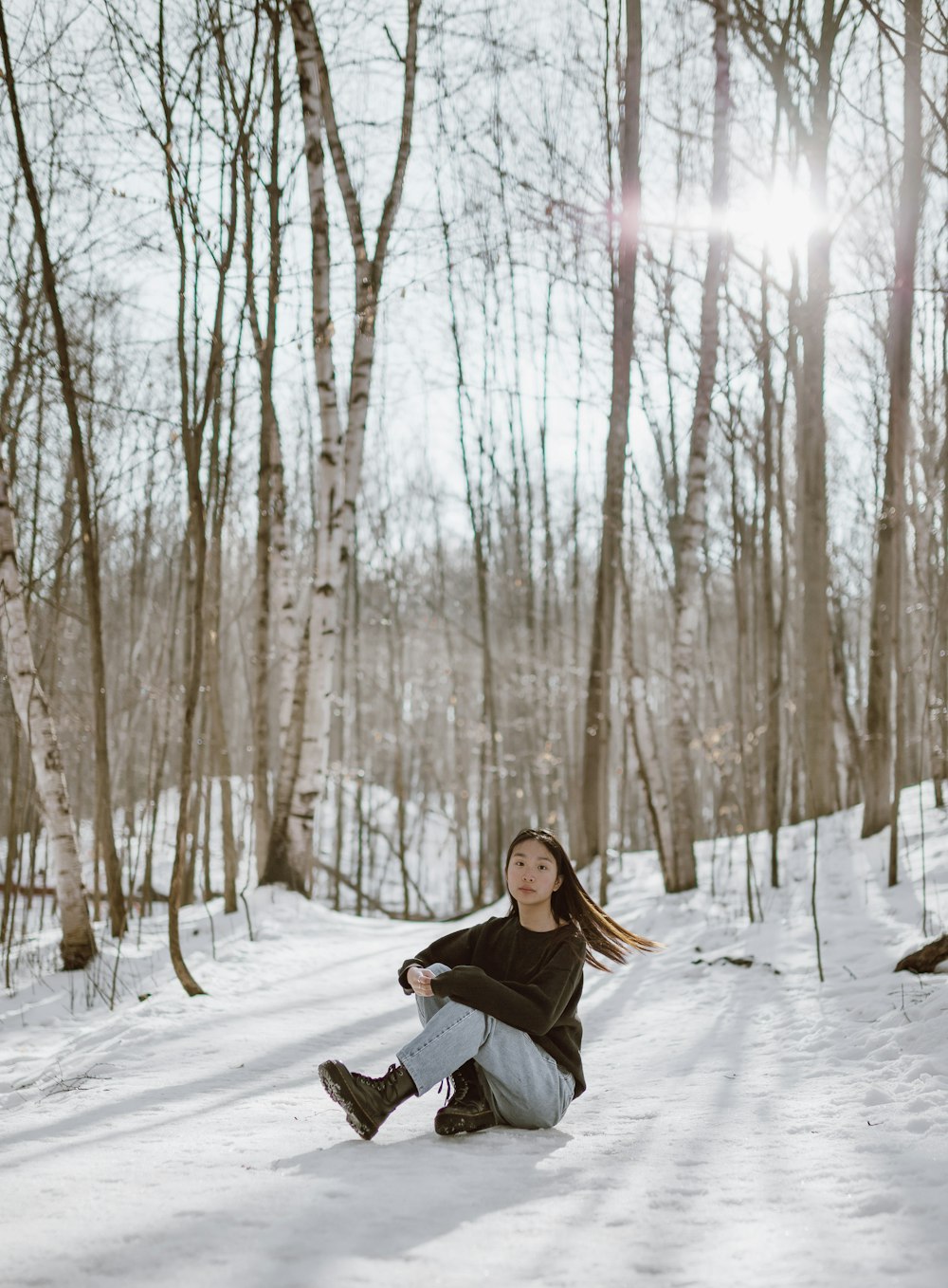 woman in black jacket sitting on snow covered ground during daytime