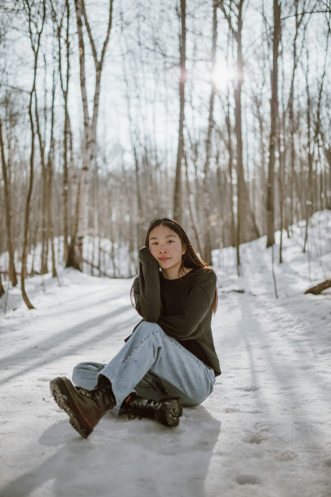 woman in brown coat sitting on brown log on snow covered ground during daytime