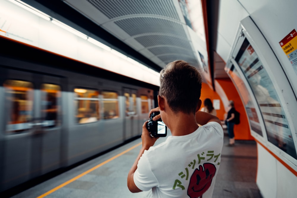 man in white crew neck t-shirt holding black smartphone