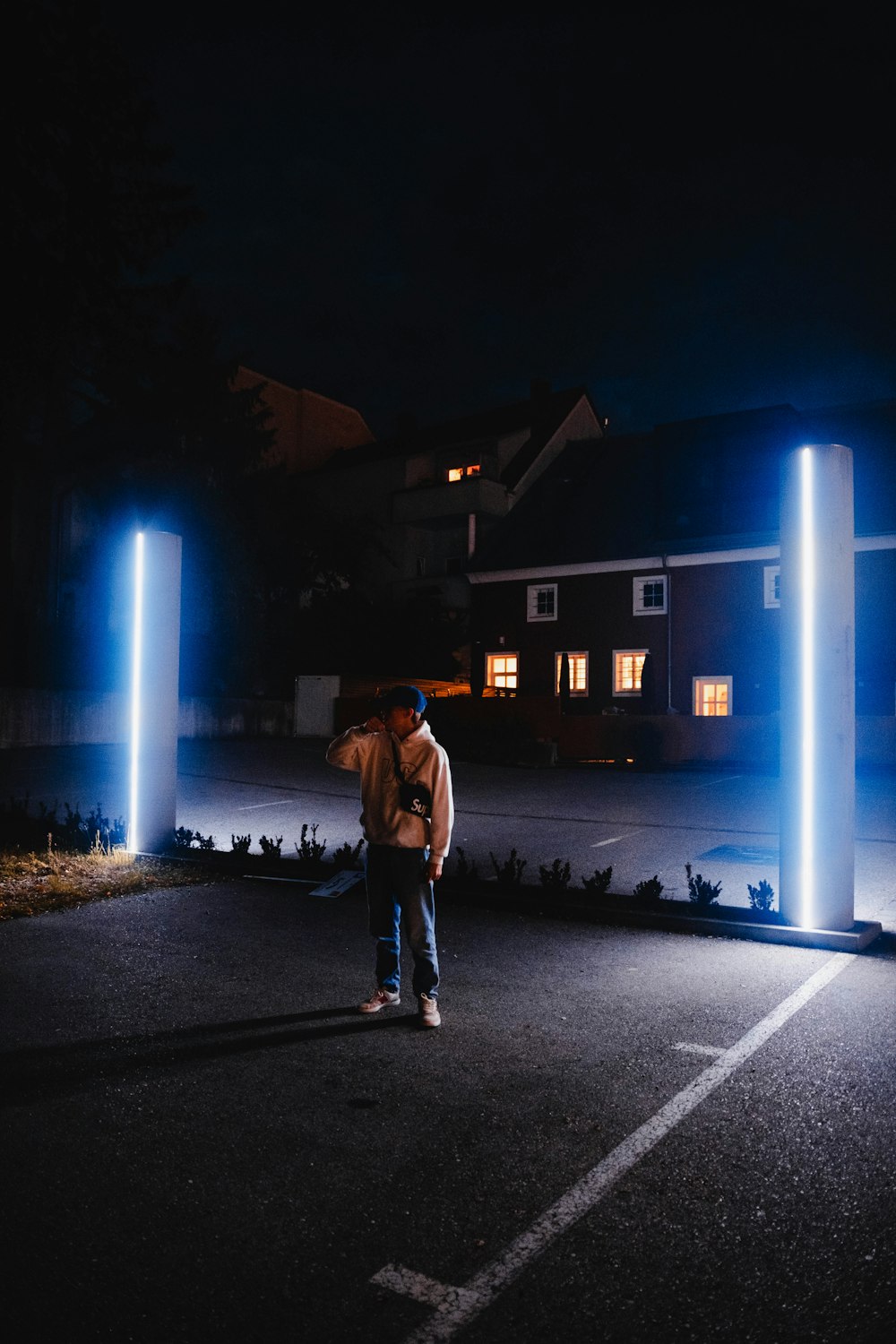 man in brown jacket standing on road during night time