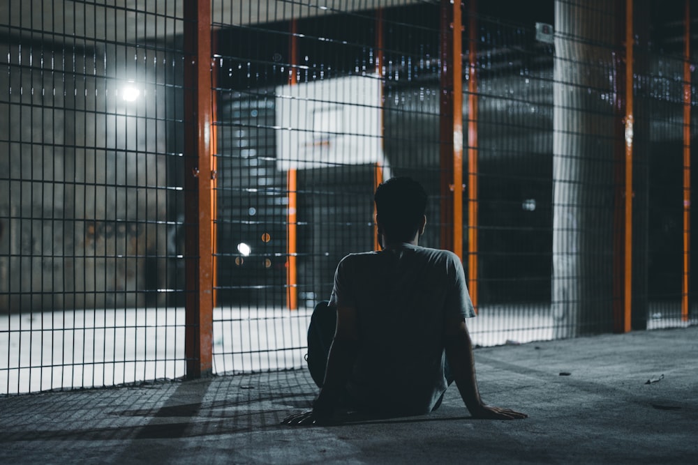 man in black jacket sitting on sidewalk during daytime