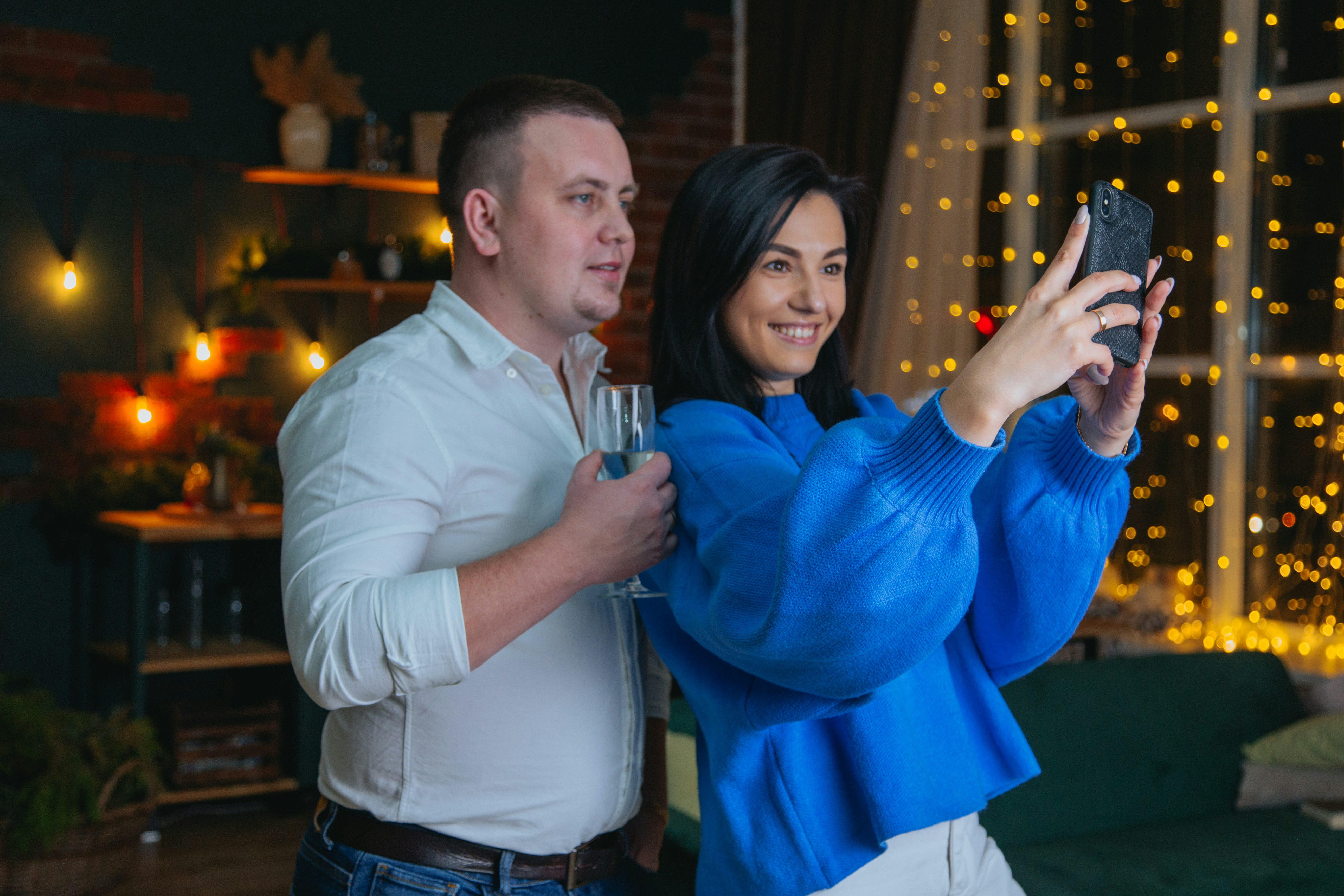 man in blue sweater holding drinking glass beside woman in blue sweater