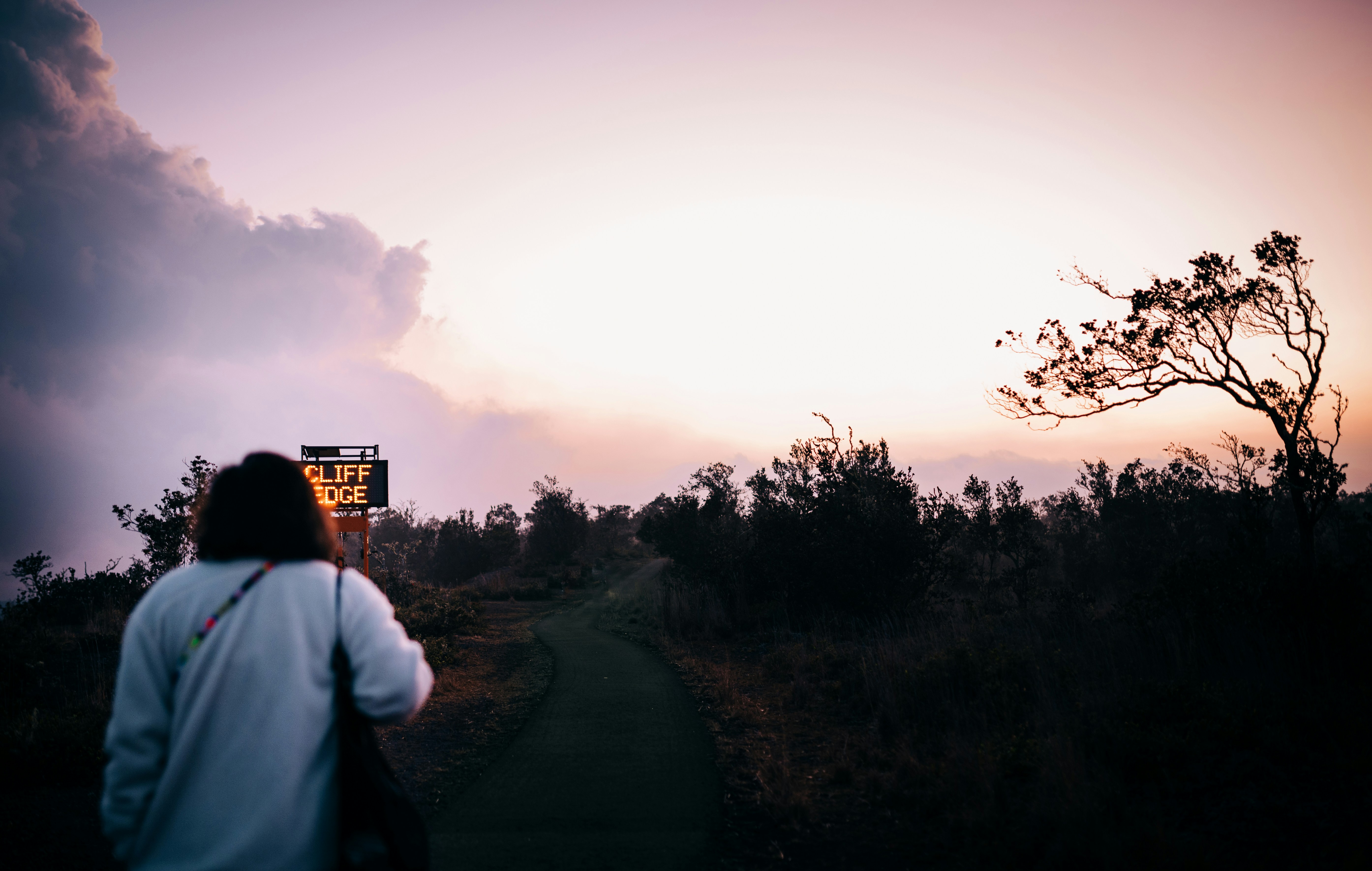 man in white shirt standing on road during sunset