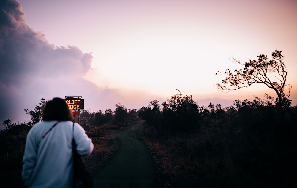 man in white shirt standing on road during sunset