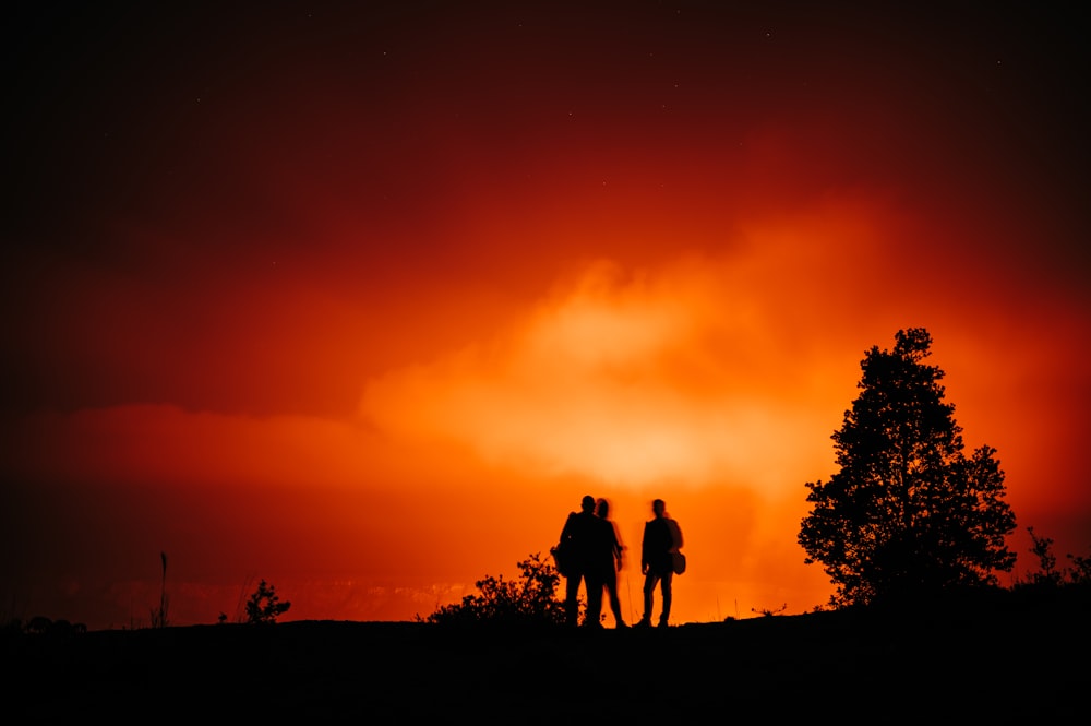silhouette of 3 men standing on ground during sunset