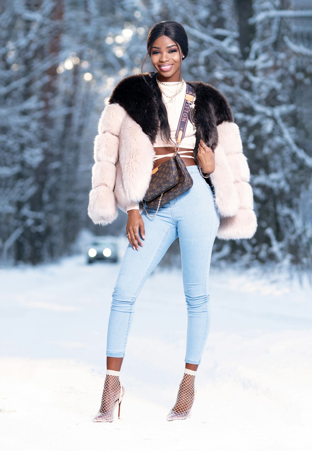 woman in white fur jacket and blue denim jeans standing on snow covered ground during daytime