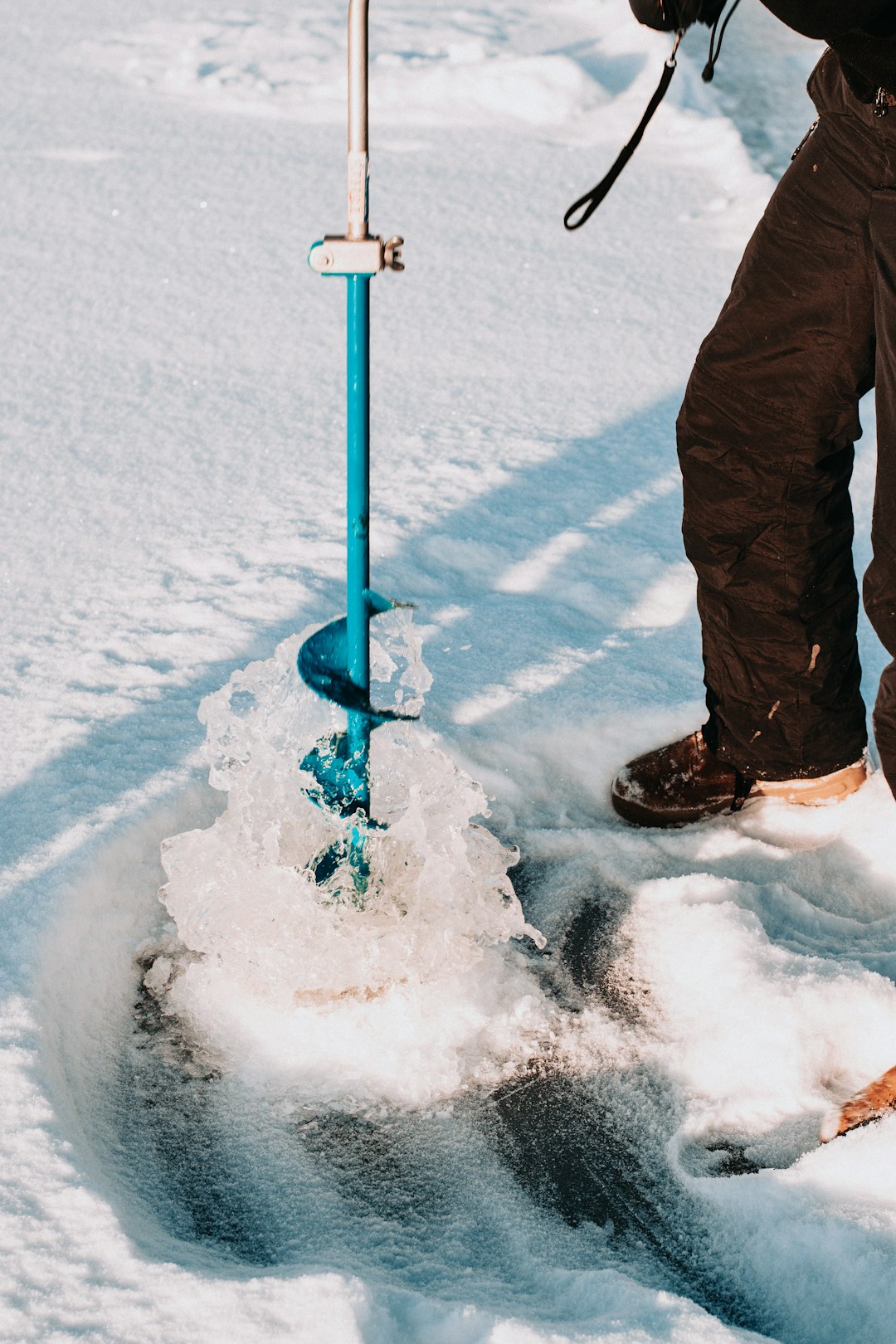 person in black pants and black winter boots standing on snow covered ground during daytime