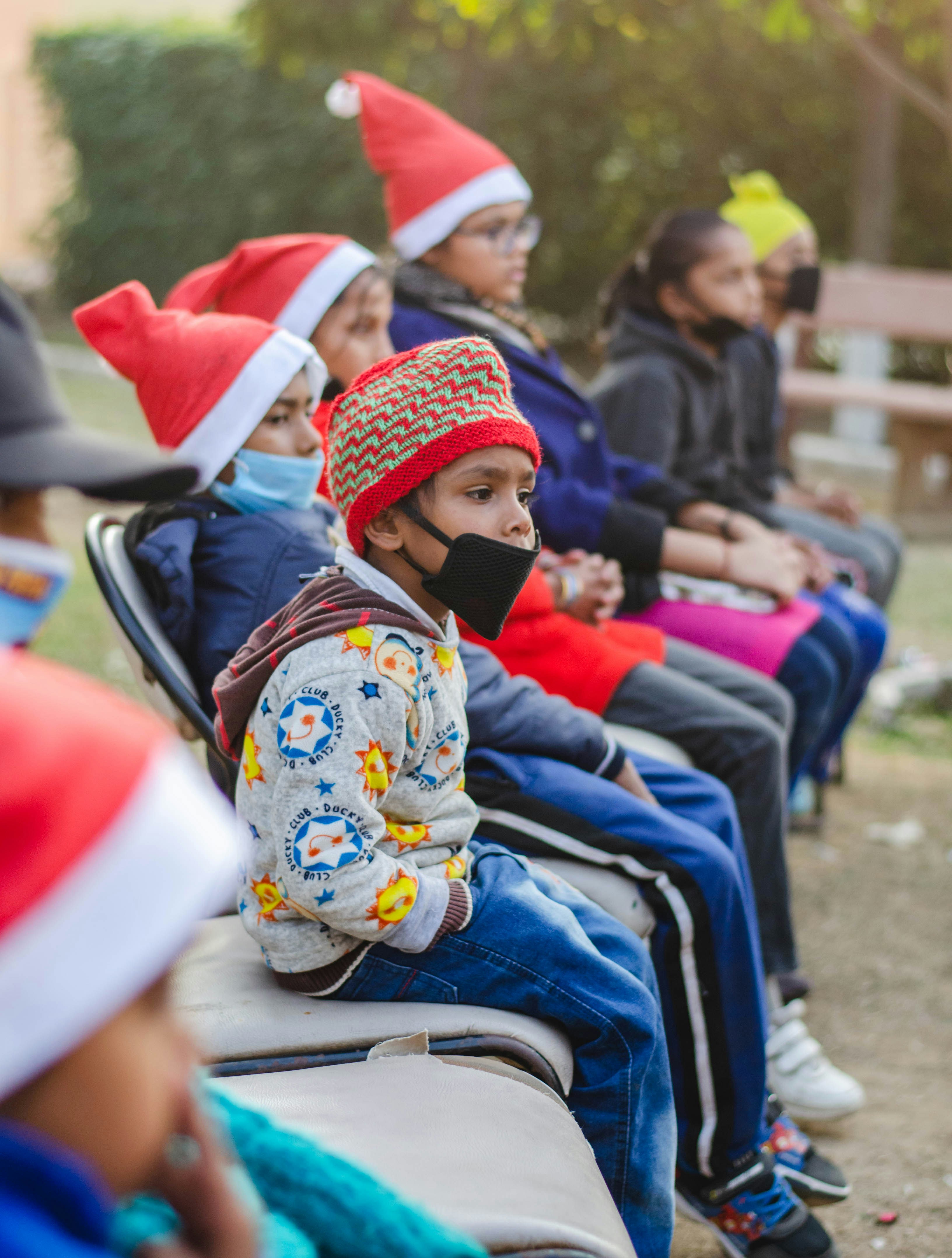 boy in blue and white sweater sitting on white plastic chair