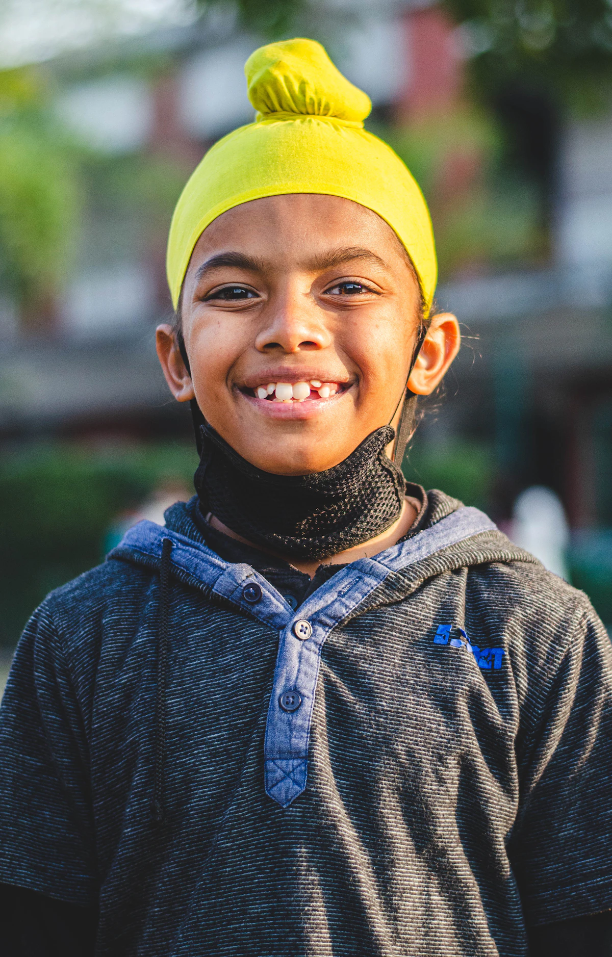 Smiling boy in a yellow beanie posing for a photo outside