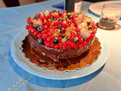 A beautifully decorated chocolate cake with fresh berries on top, sitting on a rustic wooden table.