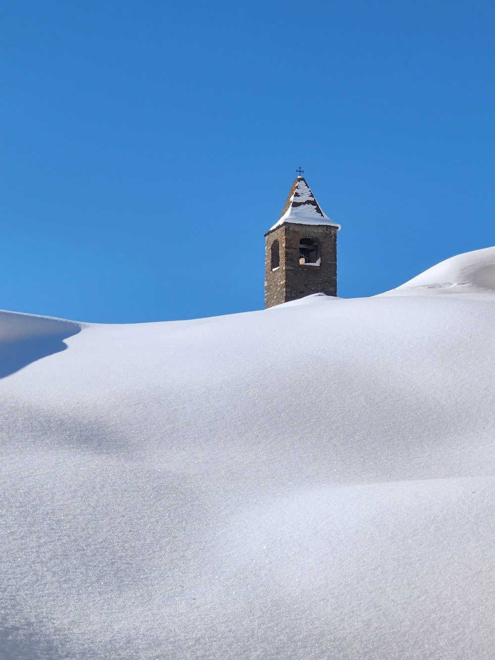 brown concrete building on white snow covered hill under blue sky during daytime